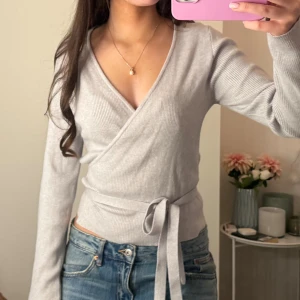 Kofta Gina Tricot  - Supersnygg ljusgrå omlottkofta från Gina Tricot med knytband. Jättebra skick, knappt använd