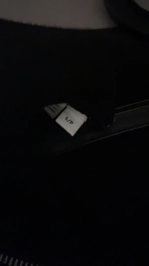 Svart stickad kofta med dragkedja - Svart stickad kofta från Peak Performance i storlek S. Koftan har en hög krage och silverfärgad dragkedja framtill. Snygga strukturerade partier ger extra stil. Perfekt för dig som gillar en clean look med lite edge.