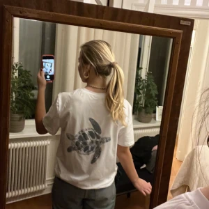 Tshirt med tryck på ryggen  - Så snygg T-shirt med en sköldpadda som tryck på ryggen 