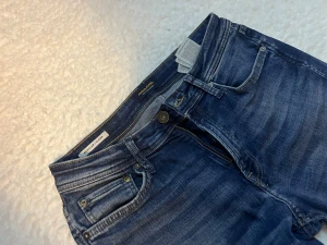 Blå jeans från Jack & Jones Clark - Snygga blå jeans från Jack & Jones, modell Clark. Jeansen har en klassisk femficksdesign, normal passform och raka ben. Materialet är slitstarkt denim i bomull. (28 midja, 30 längd)