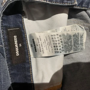 Dsquared2 Canada Jeans blå, storlek 54 - Säljer ett par Dsquared2 Canada Jeans i blå tvätt med coola slitningar och en stor röd-vit lapp med lönnlöv på bakfickan. Klassisk femficksmodell med snygga detaljer och kontrastsömmar. Materialet är jeans och passformen är normal.100% äkta köp på rabatt för 3300 men i nu läget ligger dom på nästan 8000kr.