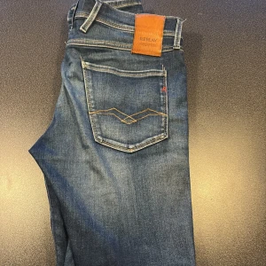 Replay Anbass Hyperflex jeans blå - Snygga Replay Anbass Hyperflex jeans i mörkblå tvätt med klassisk femficksdesign och gul kontrastsöm på bakfickorna. Slim fit-modell med stretchigt material för extra komfort.  Använda ca 10 gånger köpta helt nya på boozt för 3 månader sen! Storlek W31 L34