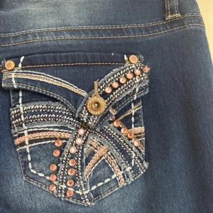 Blå bootcut jeans från Hydraulic - Snygga blå jeans från Hydraulic med bootcut passform. Baksidan har detaljerade fickor med broderier, pärlor och kontrastfärgade sömmar i beige och rosa. Jeansen har normal midja och är tillverkade i klassiskt jeansmaterial.