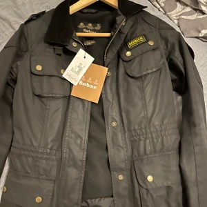 Svart jacka från Barbour - Säljer en snygg svart Barbour International Speedway jacka i nytt skick. Jackan är gjord i slitstarkt material och har en mjuk insida för extra komfort. Aldrig använd, köpt i Johnells för 3998:- 