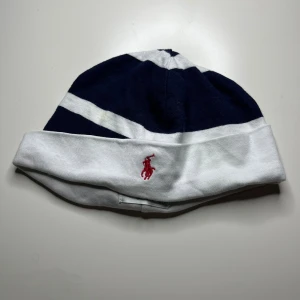 Polo Ralph Lauren mössa mörkblå och vit  - Mörkblå och vit Polo Ralph Lauren mössa till barn i mycket bra skick, pm vid intresse.
 
 Storlek: 6M
