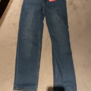 Levi's 505 blå jeans straight fit - Säljer ett par klassiska Levi's 505 jeans i blå denim med straight fit. Byxorna har normal midja, fem fickor och snygga detaljer med Levi's etiketter bak. Perfekt passform och tidlös stil för dig som gillar jeans med lite mer rakt snitt.