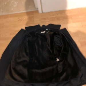 Rock från Calvin Klein - Svart rock från Calvin Klein med dubbelknäppning och bred krage. Insidan har ett mjukt, svart foder som ger extra värme. Jackan har klassisk, rak passform och är perfekt för kyliga dagar. Snygg och stilren design med knappar framtill.