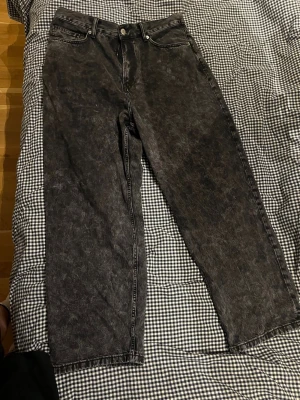Svarta wide jeans från H&M - Säljer ett par svarta jeans från H&M med cool tvättad look och breda ben. Klassisk femficksmodell med knapp och dragkedja fram. W38 L32