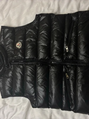 Moncler gui väst  - Stilren, lätt och varm Moncler gui väst med dragkedja och fickor. Perfekt till vardag och lager-på-lager. Pris kan diskuteras 