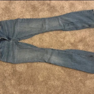 Blå bootcut jeans från LeMonde - Snygga blå jeans från MONKY med klassisk bootcut-passform. Jeansen har fem fickor, bälteshällor och en ljus tvätt som ger en chill vibe. Materialet är jeans och de har en normal midja. Perfekta för dig som gillar retrostil och vill ha ett par jeans med lite extra attityd.