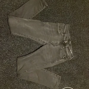 Replay Anbass svarta jeans, storlek 29 - Svarta Replay Anbass jeans med klassisk femficksdesign och snygga detaljer på bakfickorna. Jeansen har en modern, smal siluett och är tillverkade i stretchigt bomullsmaterial för extra komfort. Perfekt för dig som gillar stilrena och coola jeans. Skick 9/10
