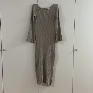 Ribbad långklänning från H&M - Säljer en snygg ribbad långklänning från H&M i beige ton. Klänningen har långärmade ärmar med lätt utsvängd form och rundad halsringning. Materialet är mjukt och stickat, vilket gör den både bekväm och stilren. Perfekt för dig som gillar enkel och trendig design. Passar även för S/M