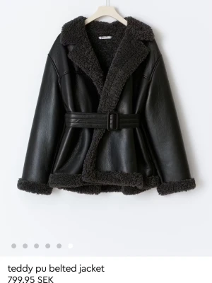 Svart teddyjacka med bälte från Gina Tricot - Säljer en svart teddyjacka med snygga detaljer i fuskpäls från Gina i storlek XS. Har endast använts en gång. 