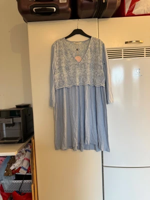 Odd Molly ljusblå spetsklänning - Superfin ljusblå klänning från Odd Molly med v-ringning och lång ärm. Överdelen har detaljerad vit spets med broderat mönster och resten av klänningen är i mjukt, flowy tyg. Perfekt för dig som gillar romantisk och bohemisk stil. Från märket Odd Molly. Storlek 2 som enligt deras storleksguide motsvarar en M. Helt ny med tags/ prislapp fortfarande kvar.  