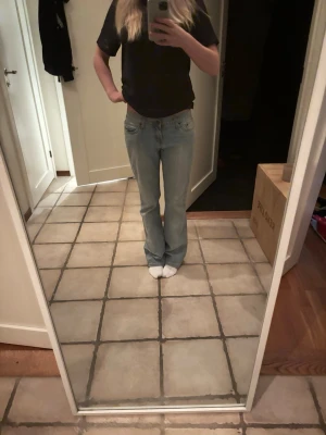Ljusblå bootcut jeans - Säljer ett par ljusblå jeans med klassisk femficksdesign och bootcut passform. Jeansen har låg midja och raka ben som blir lite vidare nedtill. Perfekta för dig som gillar en avslappnad och retro stil. Materialet är klassisk denim.