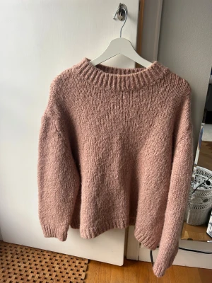 Stickad rosa tröja från Zara - Mysig stickad tröja från Zara i en ljus rosa ton. Tröjan har en rund halsringning och långa ärmar med ribbade muddar. Passformen är loose .