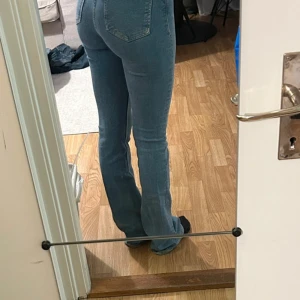Bootcut jeans från Zara ljusblå - Säljer ett par ljusblå bootcut jeans från Zara med klassisk femficksdesign och hög midja. Jeansen har en snygg passform som sitter tajt upptill och släpper vid benen. Materialet är mjukt denim i bomull med dragkedja och knapp framtill. Superfina men tyvärr för små för mig! Lite smutsiga längst ner vid benslutet men går säkert bort i en tvätt.