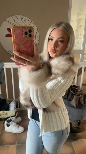 Vit pälsjacka från Alessa - Säljer en superfin vit cardigan jacka från Alessa med fluffiga pälsdetaljer i beige och brunt på krage och ärmslut. Jackan är ribbstickad och använd endast en gång. Skriv gärna för fler bilder!💞 storlek (xs/s)