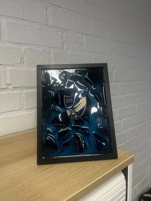 Ifk tavla - Egengjord tavla med ifk logga, den är gjord av en ifk mugg. Vi kan göra sån tavla med olika lag på. Tavlan med muggar i olika lag är alltid i samma storlek, 18cmx24cm.