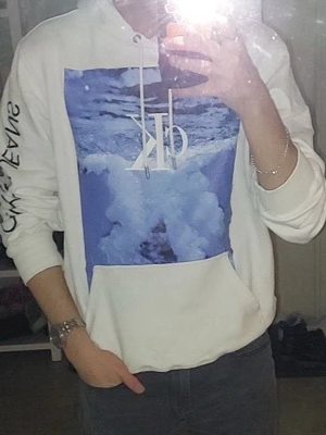 Calvin Klein hoodie - Säljer en hoodie från Calvin Klein, den är runt 4 år gammal, den har två små hål uppe vid luvan, även något mer bakom cK märket ingen som syns så, även en svart prick lite längre ner som ni ser på fjärde bilden