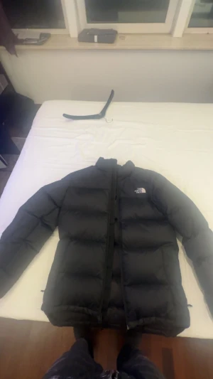 Svart pufferjacka från The North Face - Säljer en svart pufferjacka från The North Face i storlek S. Jackan har hög krage, dragkedja framtill och diskret logga på bröstet. Perfekt för kalla dagar med sin vadderade design och klassiska look. Snygg och enkel att matcha till det mesta.
