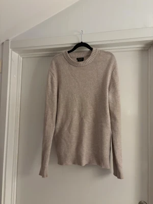 Beige stickad tröja Massimo Dutti - Säljer en beige stickad tröja från Massimo Dutti i mjuk ull och kashmir. Tröjan har rund hals med ribbad kant och långa ärmar. Enkel och stilren design som funkar till många olika looks. Perfekt för kyliga dagar.