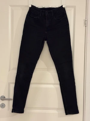 Levi’s svarta skinny jeans  - Säljer ett par svarta skinny jeans från Levi’s. Jeansen har mediumhög midja, klassisk femficksdesign och smala ben. Materialet är stretchigt för en bekväm passform och de passar perfekt till en trendig vardagslook. W27 L32