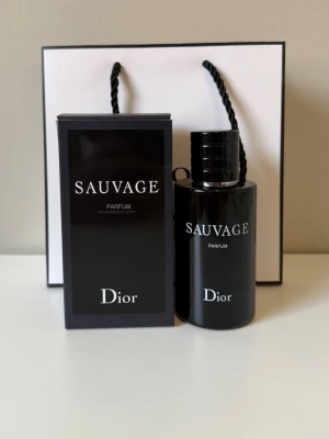 Dior Sauvage Parfum 100ml - Dior Sauvage Parfum är en exklusiv herrdoft i en elegant svart glasflaska med matchande svart kartong. Flaskan har en stilren, cylindrisk form och tydlig logotyp i vitt. Parfymen levereras i originalförpackning och ger ett lyxigt intryck.