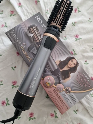 Remington Keratin Protect varmluftsborste - Remington Keratin Protect varmluftsborste i metallicgrå med svarta och roséguldsdetaljer. Borsten har roterande borsthuvud och flera värmelägen. Perfekt för att styla och ge volym till håret. Levereras med originalförpackning. Endast testad. 