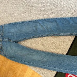 Blå raka jeans från Levi's - Klassiska blå jeans från Levi's med rak passform och femficksmodell. Jeansen har en ikonisk läderpatch bak i midjan och är tillverkade i slitstark denim. Perfekta för en avslappnad och tidlös stil.