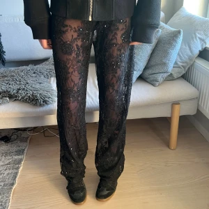 Glitter byxor  - Säljer ett par svarta meshleggings med broderade blommor och paljettdetaljer. De är transparenta och har en rak passform som sitter snyggt på benen. Perfekta för dig som vill sticka ut och addera lite edge till din outfit.
