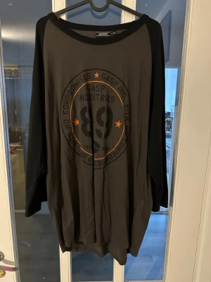 GASP långärmad t-shirt med tryck - Snygg långärmad t-shirt från GASP i mörkgrått med svarta ärmar. Stor tryckt logga och siffran 89 framtill, samt orange detaljer. Perfekt för dig som gillar sportig och avslappnad stil.