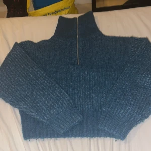 Grön stickad halvzip tröja - Mysig grön  stickad tröja med hög krage och halv dragkedja framtill. Tröjan har grov ribbstickning, långa ärmar och breda muddar vid ärmslut och nederkant. Perfekt för lager på lager och en avslappnad stil.