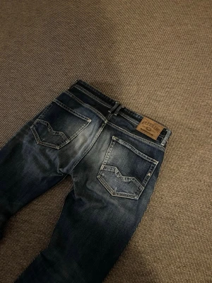 Replay blå jeans straight fit - Säljer ett par Replay jeans i blå tvätt med snygga slitningar och raka ben. Passformen är straight och materialet är robust denim som sitter skönt hela dagen. Lite slitet i skrevet annars perfekta. Priset kan diskuteras vid snabb affär och vid minsta fundering tveka inte på att höra av dig.