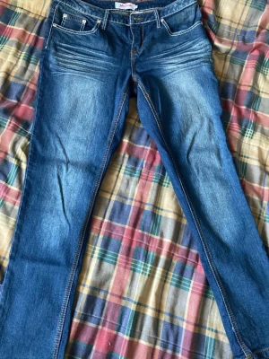 Blå skinny jeans med vita sömmar - Snygga blå skinny jeans med vita kontrastsömmar och klassisk femficksdesign. Jeansen har lätt slitning framtill och är i stretchigt denimtyg för en bekväm passform. Perfekta för en trendig och avslappnad stil.