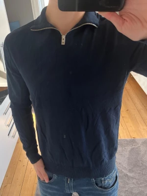 Mörkblå Halfzip - Mörkblå Halfzip från Jack and Jones i stl M. Tröjan passar bra på de som brukar ha medium, orginalpris 499. Använts 3-5 gånger, alltså bara tagit plats i garderoben. Underarmarna töjs lätt ut om man drar upp ärmarna, men de återställs efter en tvätt igen - men därav det billiga priset. 
