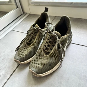 Nike Air Max 270 i olivgrönt mesh - Nike Air Max 270 sneakers i olivgrönt med ventilerande mesh-ovandel och klassisk Air Max-sula. Snygg sportig look med snörning och diskret Swoosh på sidan. Perfekta för dig som gillar streetstyle och bekväma skor med modern vibe.
