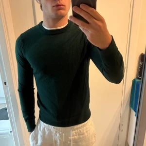 Mörkgrön merinoullströja från Riley - Mörkgrön, stilren tröja från Riley i mjuk merinoull. Klassisk rund halsringning och långärmad modell med normal passform. Perfekt för lager-på-lager och enkel att matcha med olika outfits. Mycket bra skick, sitter som xs