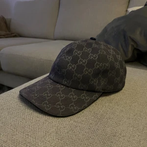 Gucci keps med GG-mönster - Snygg keps från Gucci i blå färg med klassiskt GG-monogram över hela kepsen. Justerbar rem baktill i mörkblå läder och insida i ljus textil. Perfekt accessoar för dig som vill sticka ut med lyxig streetstyle.