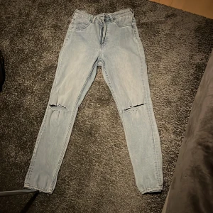 Ljusblå high waist curvy jeggings - Säljer ett par ljusblå curvy jeggings från H&M med hög midja och ankellängd. Byxorna har skinny fit och slitna knän för en trendig look. Perfekta för dig som gillar stretchiga jeans med tajt passform.