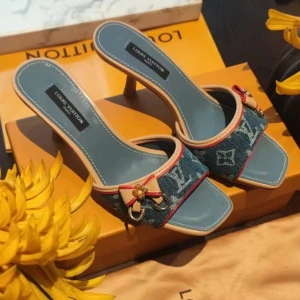 Louis Vuitton sandaler med klack och monogram - Snygga Louis Vuitton sandaler med låg klack och fyrkantig tå. Finns i blått, svart och vitt med klassiskt LV-monogram, detaljer i beige och rött samt guldfärgade metalldetaljer och rosett framtill. Materialmix av skinn och jeans eller syntet. Perfekta för dig som vill sticka ut.