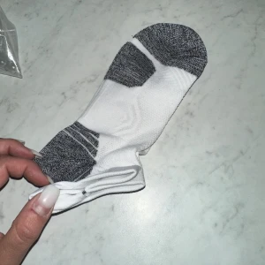 Vita och grå sportstrumpor stödstrumpor  - Stimulerar blodcirkulationen: Effektiviserar transporten av syrefattigt blod tillbaks till hjärtat och minskar trötthet, svullnad och ömhet i benen. Förebyggande: Regelbundet användande minskar risken för att drabbas av åderbråck och andra venösa besvär.Användningsområden: Används med fördel dagligen. Passar utmärkt för dig som står upp/sitter ner under långa perioder i arbetet, för dig som ska resa långt och för dig som är gravid.