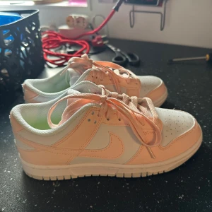 Nike Dunk Low i ljusrosa och vitt - Säljer ett par Nike Dunk Low sneakers i en fräsch kombo av ljusrosa och vitt. Bara provade 