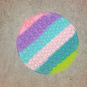 Pop It Fidget Toy Rund - Stor rund Pop It fidget-leksak i pastellfärger: rosa, lila, blå  och gul. Enkel att rengöra och använda för både barn och vuxna.