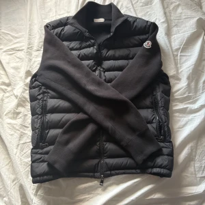 Moncler cardigan - Svart Cardigan från Moncler ” storlek L” men sitter som S/M. stickade ärmar, dragkedja framtill, två dragkedjefickor och Moncler-logga på ärmen. polyester och stickad ull, inga defekter. Kan inte garantera om den är äkta eller inte, Jag köpte den för 1,8k nydligen. Jag är 185cm och den passar utmärkt på mig. Säljer för ja vill köpa annan cardigan🙌🏻😊