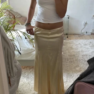 Ljusgul långkjol i satin från H&M - Supersnygg ljusgul långkjol i glansigt satinmaterial med lätt utsvängd passform från HM. Kjolen har en enkel midja utan synliga detaljer och faller snyggt längs benen 🌸