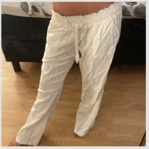 Vita linnebyxor med snörning - Säljer ett par vita linnebyxor med bred resår i midjan och snörning framtill. Byxorna har raka ben, sidfickor och är tillverkade i ett luftigt linnematerial. Perfekta för varma dagar och chill vibes. Säljer pågrund av att dom är förstora dom är lite söndriga vid snöret men inget man tänker på 