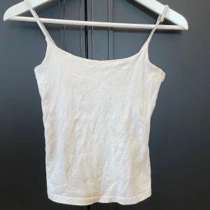 Vit linnetopp med smala axelband - Enkel och stilren vit linnetopp med smala axelband och rak passform. 