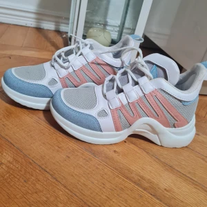 Pastellfärgade sneakers med snörning - Snygga sneakers i pastellfärger med vit, ljusblå och rosa detaljer. Ovandelen är i mesh och syntet med coola paneler och vit tjock sula. Skorna har snörning och en sportig vibe som passar perfekt till streetwear eller casual outfits.