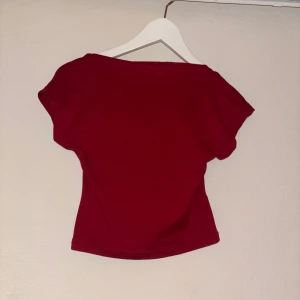 Röd topp med öppen rygg - Snygg röd topp i bomull med korta ärmar och en riktigt cool öppen rygg. Modellen är tight och croppad, perfekt att styla med höga jeans eller kjol. Enkel men ändå unik med sin djupa ryggdetalj. Använd ett fåtal gånger då jag tycker den är för cropad 